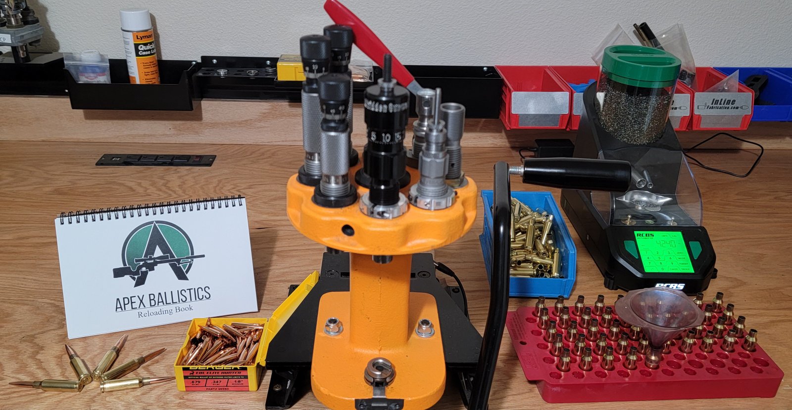 Apex Ballistics Reloading Log Book displayed on a reloading bench with presses, brass, and tools